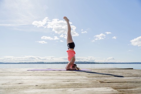 Caucasian woman practicing yoga on wooden dock