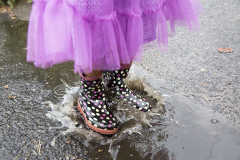 Mixed race girl playing in puddle