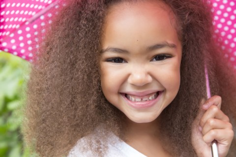 Mixed race girl smiling under umbrella