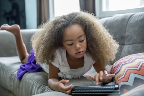 Mixed race girl using digital tablet on sofa