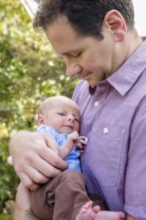 Father holding newborn son outdoors