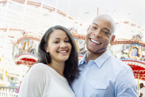 Mixed race couple smiling at amusement park