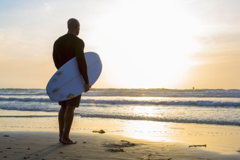 Mixed race man holding surfboard on beach