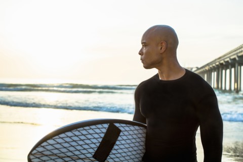 Mixed race man holding surfboard on beach