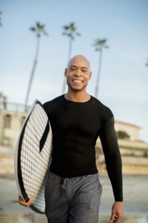 Mixed race man carrying surfboard on beach