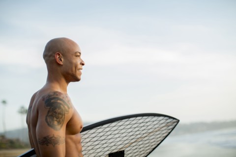 Mixed race man holding surfboard on beach