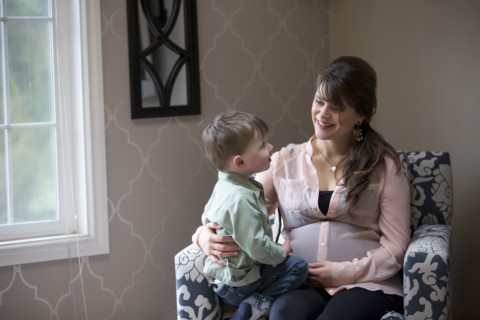 Pregnant Caucasian mother sitting with son