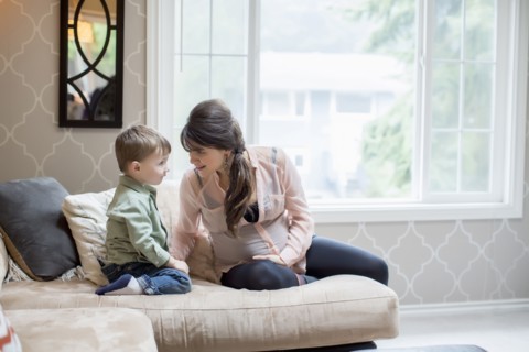 Pregnant Caucasian mother sitting with son in living room