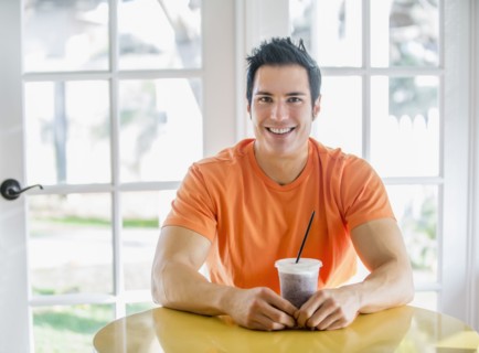 Caucasian man drinking smoothie in kitchen