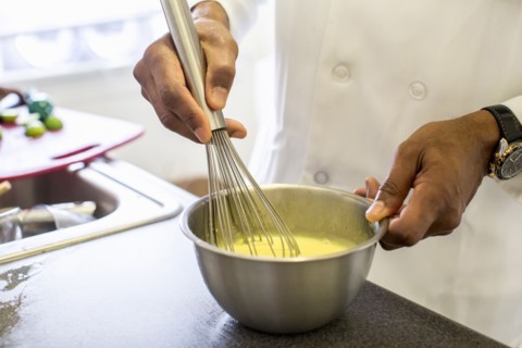 Black chef whisking eggs in restaurant