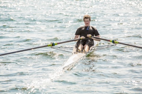Mixed race teenage boy rowing on lake