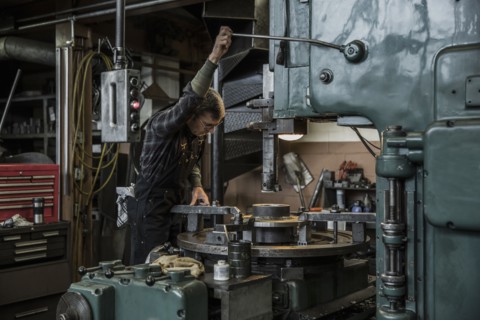 Caucasian man using machinery in metal shop