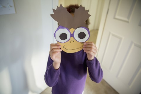 Mixed race girl holding mask over face