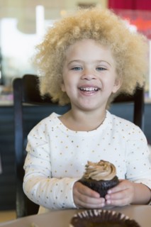 Mixed race girl having cupcake in bakery