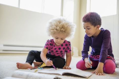 Mixed race sisters coloring on floor