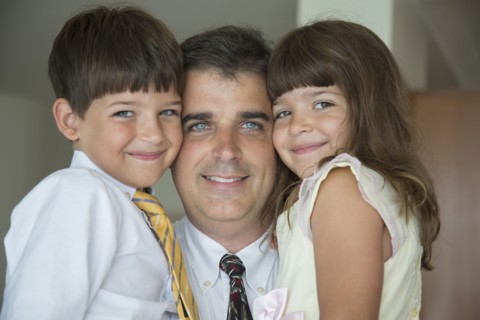 Caucasian father and children smiling in formal wear
