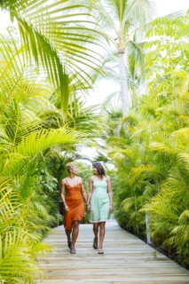 Lesbian couple holding hands on tropical walkway
