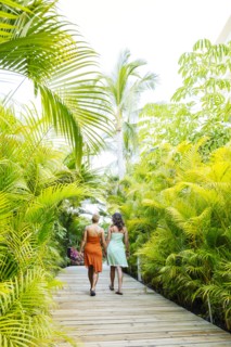 Lesbian couple holding hands on tropical walkway