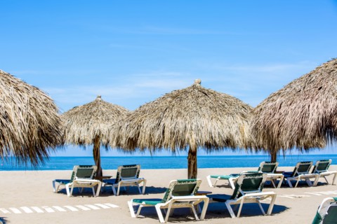 Lounge chairs and thatch umbrellas on tropical beach