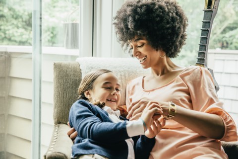 Mixed race mother holding daughter in armchair