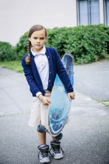 Mixed race girl holding skateboard on sidewalk