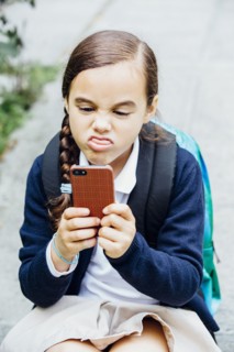 Mixed race girl making a face at cell phone