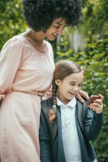 Mixed race mother and daughter using cell phone together