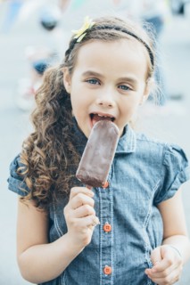 Mixed race girl eating fudgesicle on city street