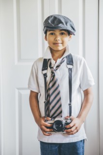 Mixed race boy wearing camera on strap