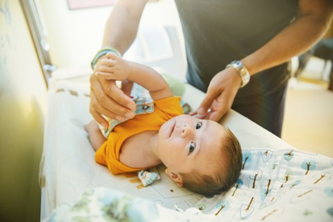 Caucasian father changing diaper of baby boy