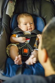 Caucasian father admiring baby boy in car seat