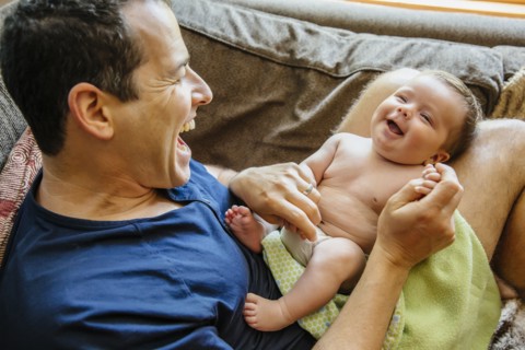 Caucasian father laughing with baby boy on sofa