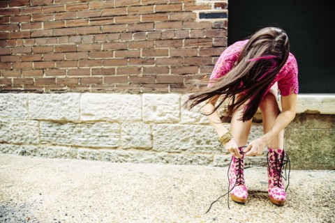 Caucasian woman tying boots on sidewalk