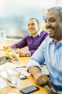 Businessmen laughing in office meeting