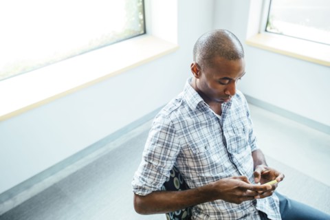 Black man using cell phone in office