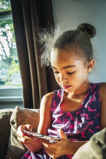 Mixed race girl using cell phone on sofa