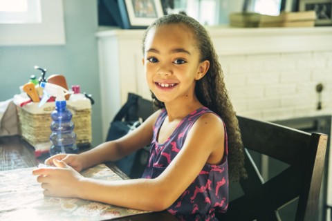 Mixed race girl smiling at kitchen table