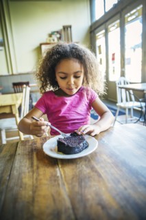 Mixed race girl eating dessert in cafe