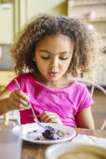 Mixed race girl eating dessert in cafe
