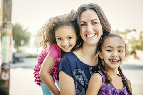 Mother and daughters smiling outdoors