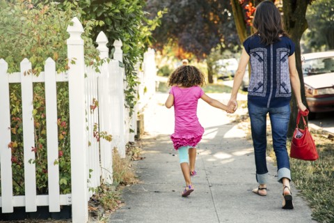 Mother and daughter holding hands on sidewalk