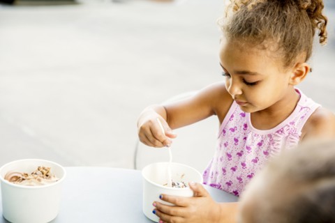 Mixed race girl eating ice cream at outdoor cafe