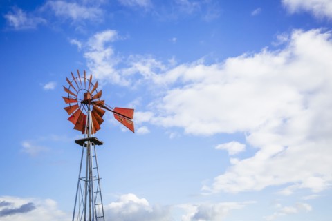 Low angle view of windmill turning under blue sky