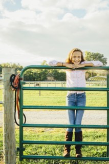 Caucasian girl standing on fence on ranch