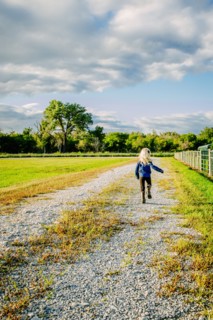 Caucasian girl walking on dirt road on ranch