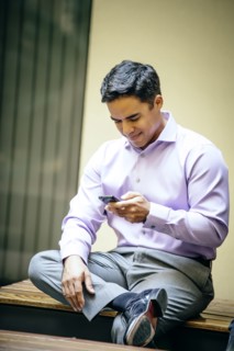 Mixed race businessman using cell phone in office courtyard