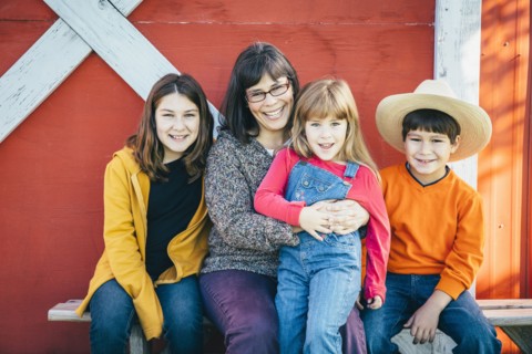 Caucasian mother and children smiling outside barn
