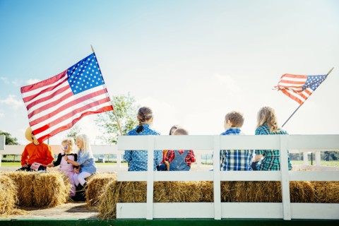 Caucasian children waving American flags on hay ride