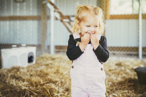 Caucasian girl biting fingers in barn