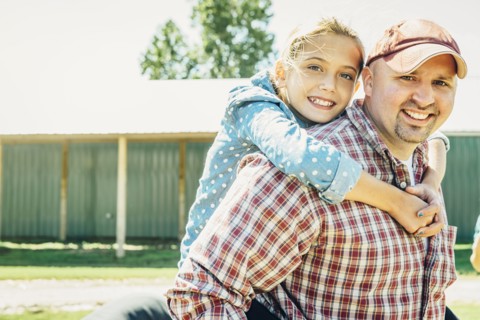 Caucasian father carrying daughter piggyback on farm
